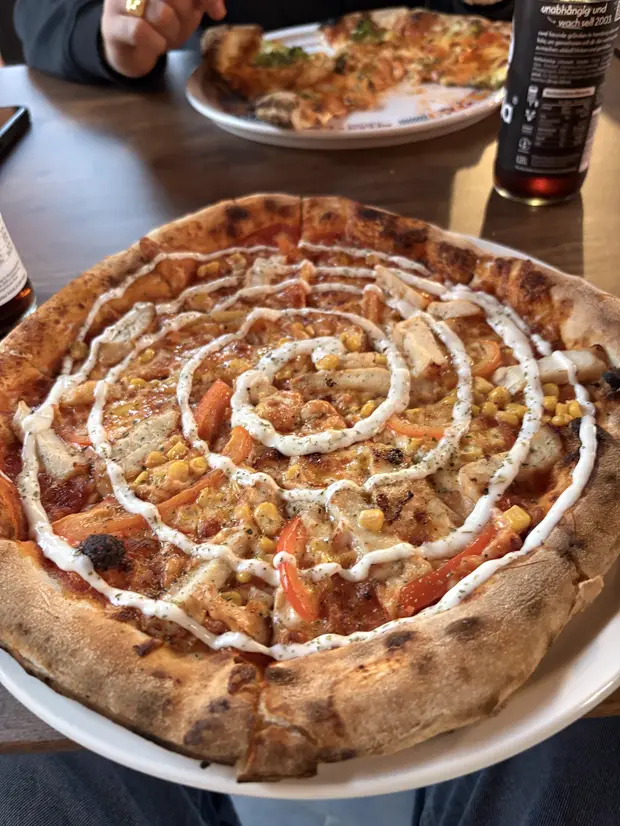 Chicken Cream Pizza mit Hähnchen, Mais, Paprika und einer Aioli-Spirale.