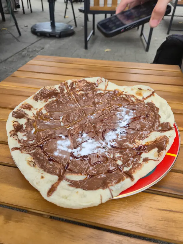 Nutella-Pizza auf einem Holztisch vor dem Laden.