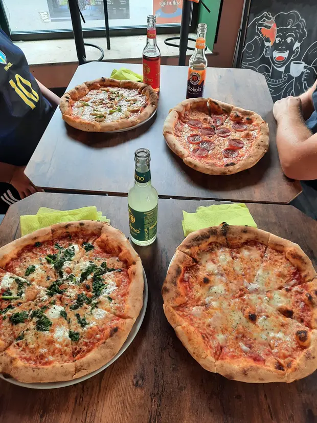 Vier Pizzen auf zwei Tischen: Spinat, Salami und zwei Margherita, dazu Limonaden.