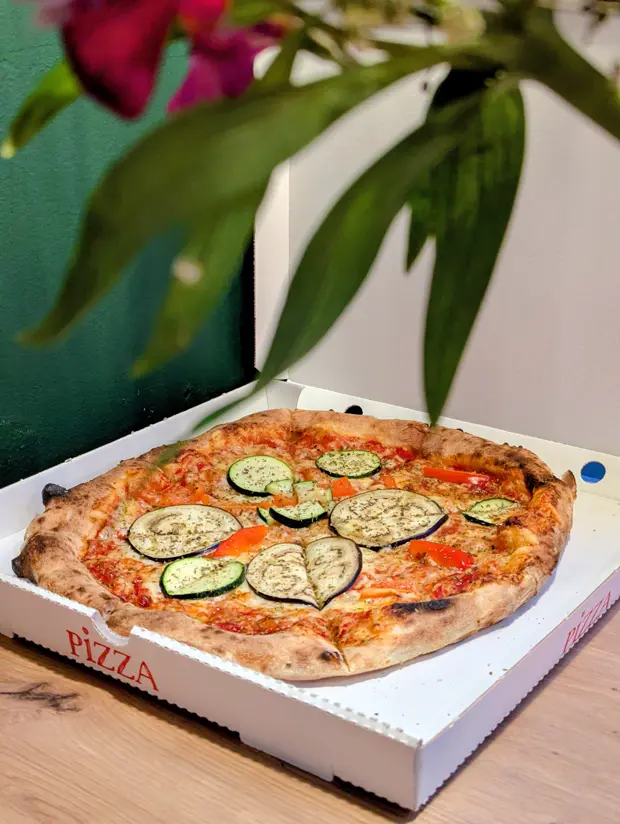 Vegetarische Pizza mit Aubergine, Zucchini und Paprika im Pizzakarton.
